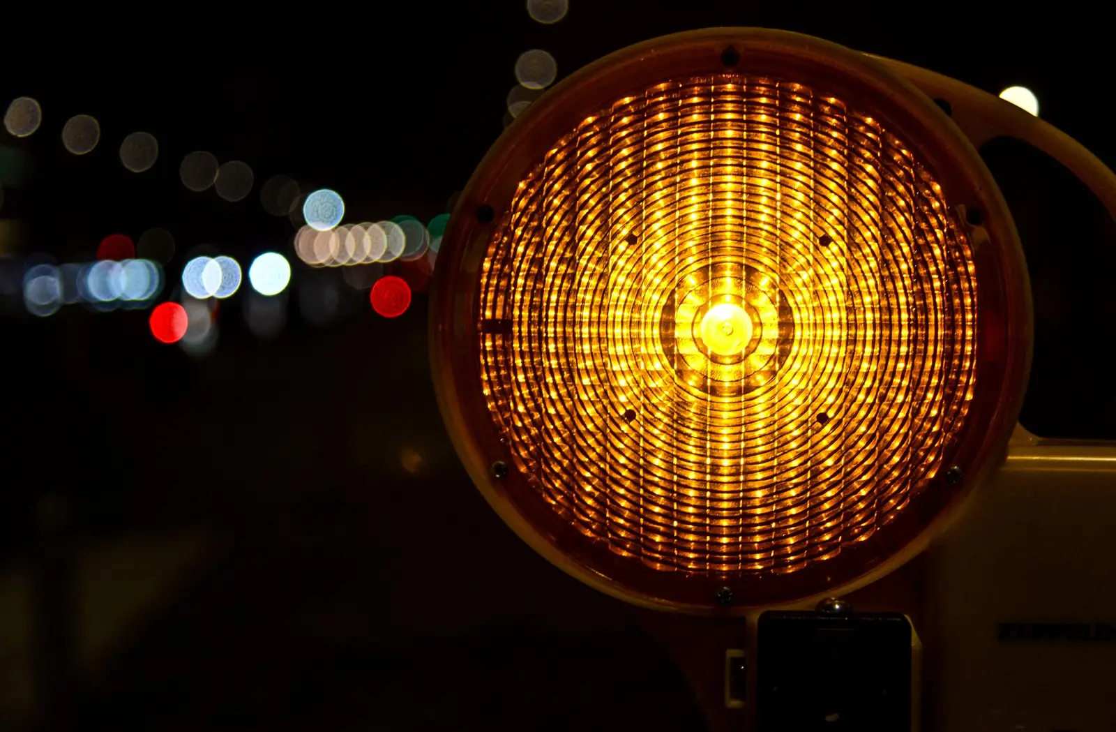 An amber warning beacon glowing beside a road at night