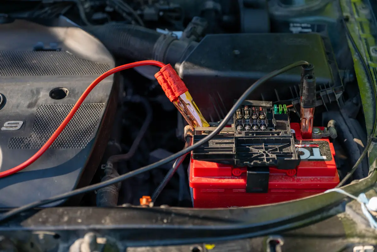 Red and black jumper clamps on a car battery terminal