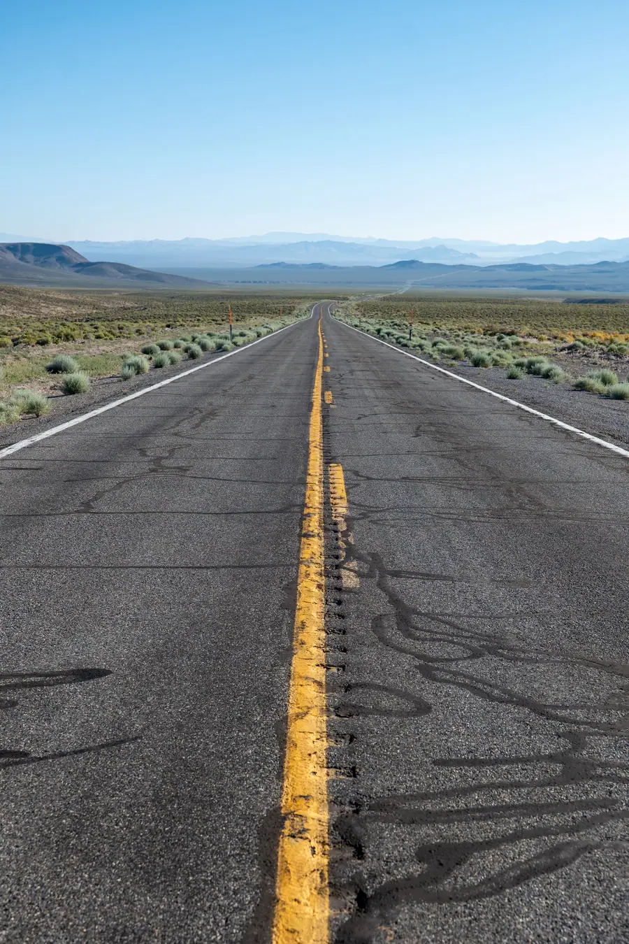 A Nevada desert highway with a double yellow center line stretching to the horizon