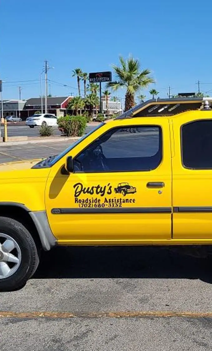 The driver's door of Dusty's yellow Xterra, lettered Dusty's Roadside Assistance (702) 680-3132, in Las Vegas