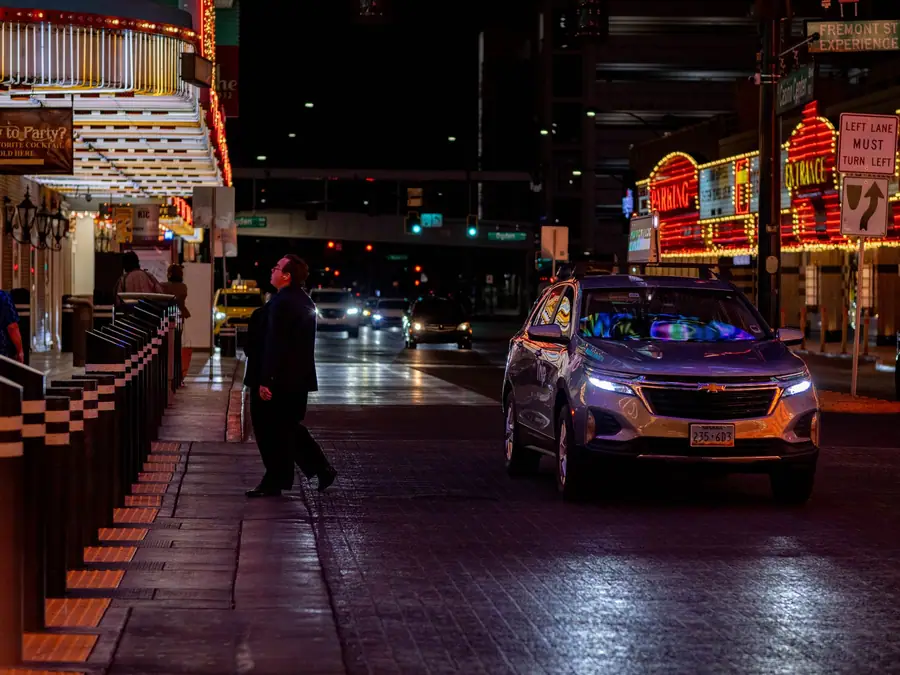 Fremont Street in downtown Las Vegas at night, an SUV passing under the casino lights
