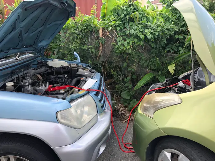Jumper cables running between two cars with their hoods open for a jump start