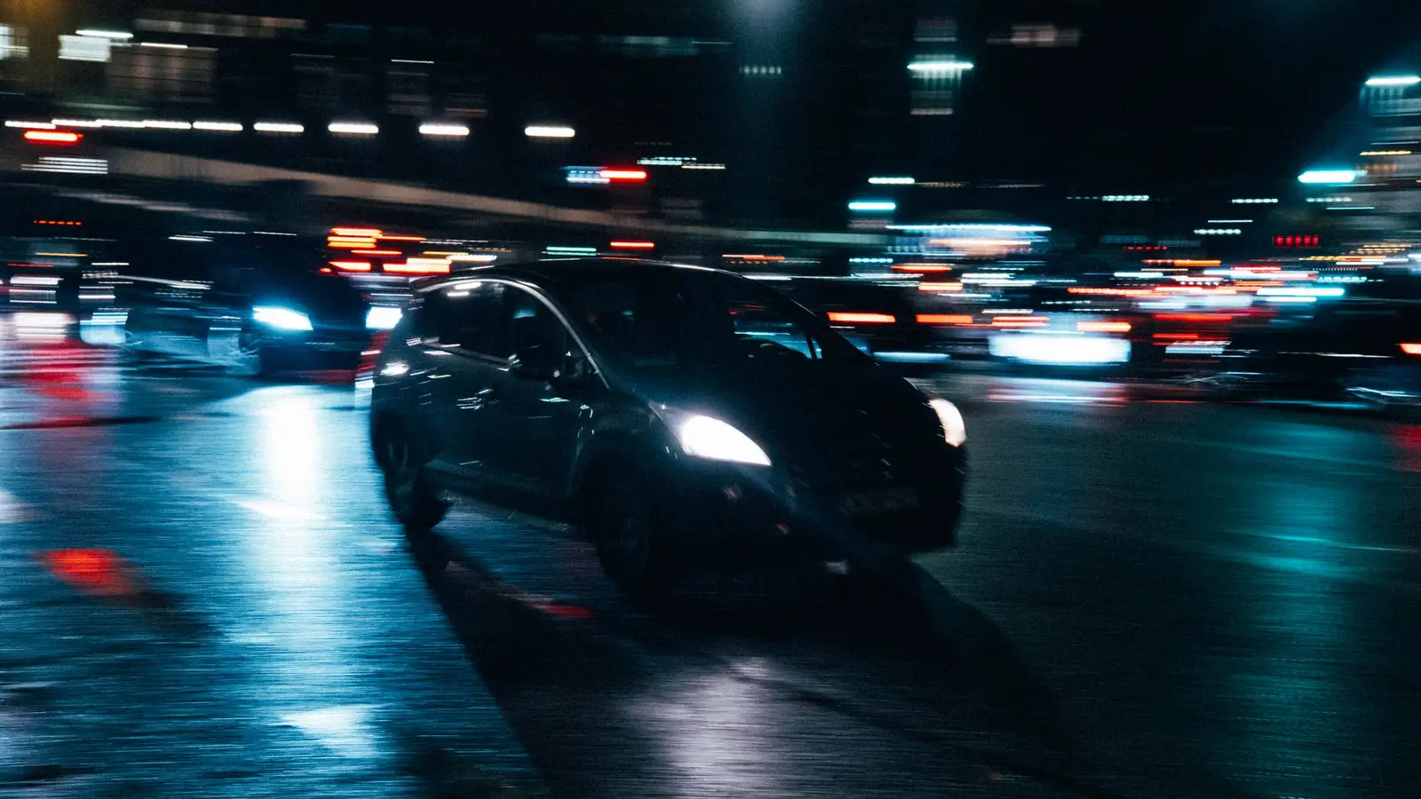 A car on a city road at night with streaks of traffic light behind it