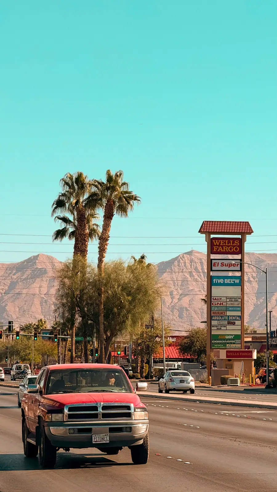 A Las Vegas boulevard lined with palm trees, the Spring Mountains behind