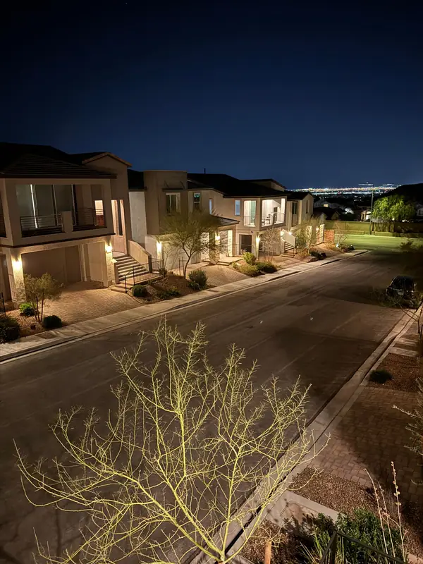 A Las Vegas neighborhood street at night, two-storey homes lit along the curb