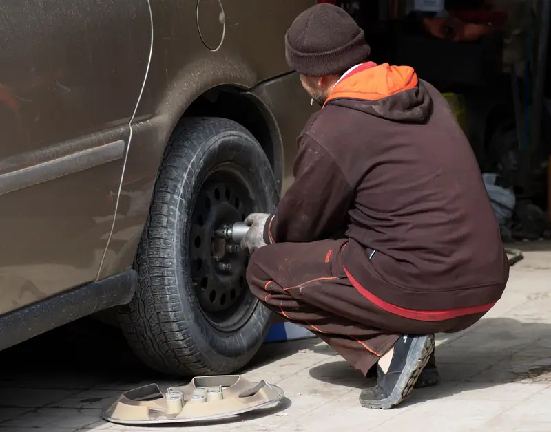 A wheel coming off a car with an impact wrench during a roadside tire change