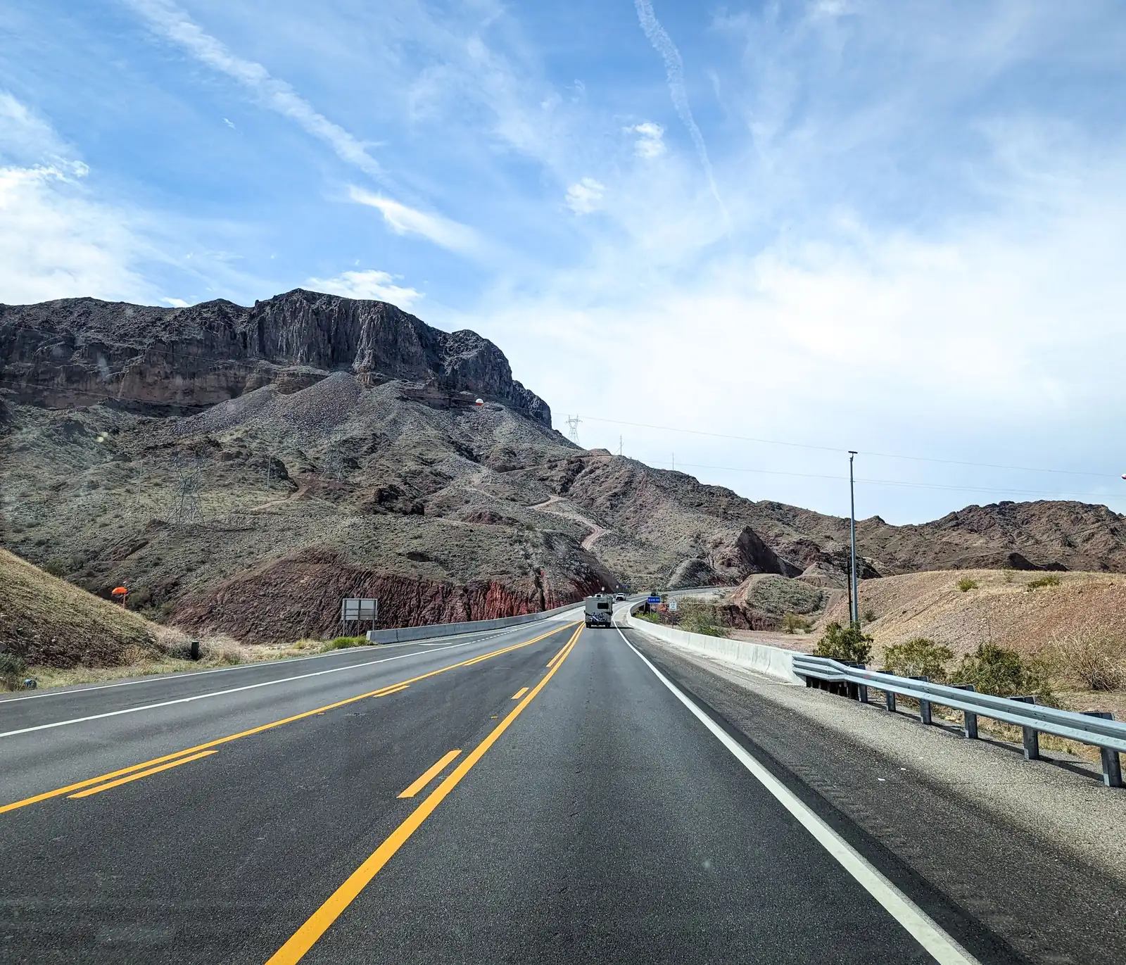 U.S. Route 95 running through rocky desert hills under a blue sky